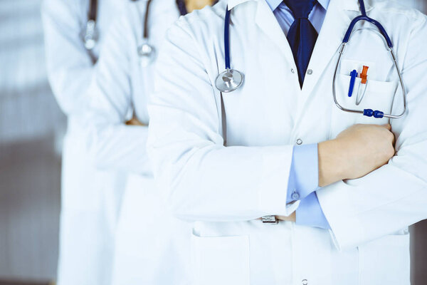 Group of modern doctors standing as a team with crossed arms and stethoscopes in hospital office. Physicians ready to examine and help patients. Medical help, insurance in health care