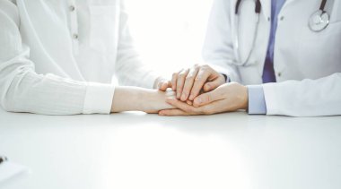 Doktor ve hasta klinikteki masada yan yana oturuyorlar. Kadın doktorlara odaklan. Kadına güven veren eller, sadece eller, yakın çekim. Tıp konsepti.