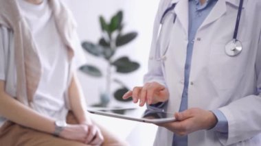 Doktor hasta yanında otururken tablet bilgisayar kullanıyor. Bilinmeyen kıdemli hekim iş başında. İlaç ve sağlık hizmetleri kavramı.