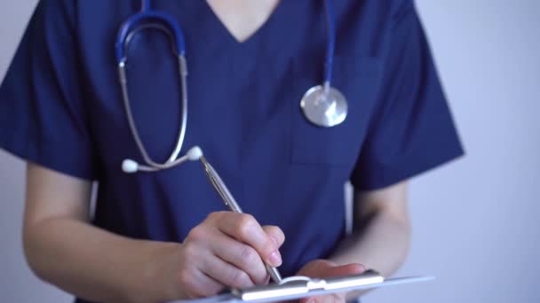 Lekarz Kobieta Pomocą Podkładki Sporządzania Notatek Medycznych Stojąc Pobliżu Szarego — Wideo stockowe
