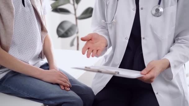 医生和小孩都在诊所里 特写镜头 未知的女医生用剪贴板填写接近小男孩的医疗表格 医学概念 — 图库视频影像