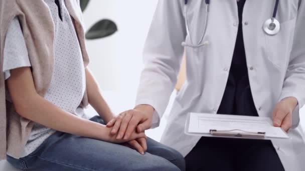 Doktor Uspokajający Pacjenta Gdy Oboje Siedzą Rozmawiają Czymś Naprzeciwko Siebie — Wideo stockowe