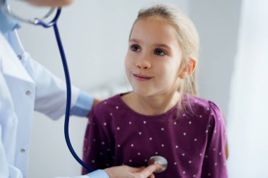 Her zamanki tıbbi muayenede gülümseyen çocuk hasta. Evde doktor ve çocuk hasta var. Tıp, sağlık hizmetleri kavramları.