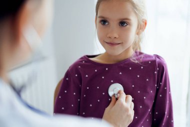 Her zamanki tıbbi muayenede gülümseyen çocuk hasta. Evde doktor ve çocuk hasta var. Tıp, sağlık hizmetleri kavramları.