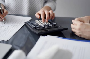 Müşteri için vergi sayarken hesap makinesi ve dizüstü bilgisayar kullanan kadın muhasebeci. İş denetimi ve finans kavramları.