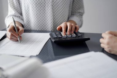 Müşteri için vergi sayarken hesap makinesi ve dizüstü bilgisayar kullanan kadın muhasebeci. İş denetimi ve finans kavramları.