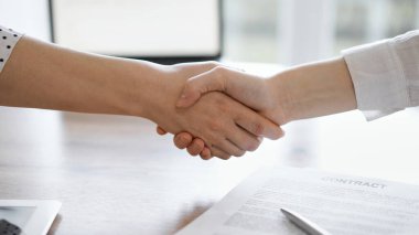 İş adamları kontrat kağıtlarının üzerinde el sıkışıyor. Tahta masaya yeni imzalanmış. Kapatın. Toplantıdaki avukatlar. Takım çalışması, ortaklık, başarı kavramı.