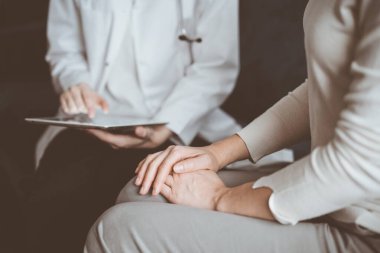 Doktor ve hasta klinikteki koltukta oturuyor. Kadın kadın ellerine odaklan, yakın çekim. Tıp konsepti.