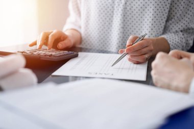 Müşteri için vergi sayarken hesap makinesi ve dizüstü bilgisayar kullanan kadın muhasebeci. İş denetimi ve finans kavramları.