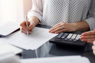 Müşteri ile vergileri sayıp tartışırken hesap makinesi ve dizüstü bilgisayar kullanan kadın muhasebeci. İş denetimi ve finans kavramları.