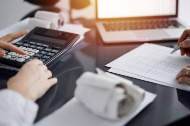 Müşteri için vergi sayarken hesap makinesi ve dizüstü bilgisayar kullanan kadın muhasebeci. İş denetimi ve finans kavramları.