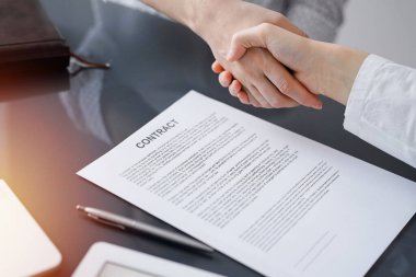 Ofisteki cam masada otururken sözleşmeyi imzalayan işadamları, yakın plan. Toplantıda ortaklar ya da avukatlar birlikte çalışıyor. Takım çalışması, ortaklık, başarı kavramı.