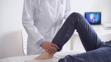 Doktor ve hasta klinikte olağan sağlık kontrolündeler. Terapist genç bir kadının dizini muayene ediyor. Tıp konsepti.