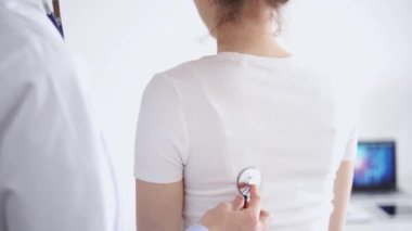 Doktor ve hasta klinikte olağan sağlık kontrolündeler. Terapist, genç bir kadını steteskopla muayene ediyor. Tıp konsepti.