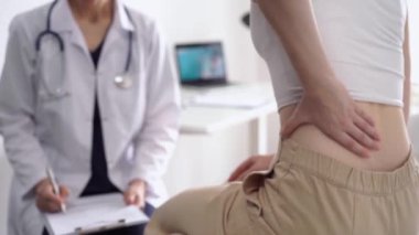 Doktor ve hasta klinikte. Beyaz önlüklü ortopedik bir kadın sırtını ovalarken not almak için pano kullanıyor, kapat. Tıp, fizik tedavi konsepti.
