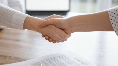 İş adamları kontrat kağıtlarının üzerinde el sıkışıyor. Tahta masaya yeni imzalanmış. Kapatın. Toplantıdaki avukatlar. Takım çalışması, ortaklık, başarı kavramı.
