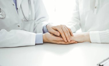 Doktor ve hasta klinikteki masada yan yana oturuyorlar. Kadın doktorlara odaklan. Kadına güven veren eller, sadece eller, yakın çekim. Tıp konsepti.