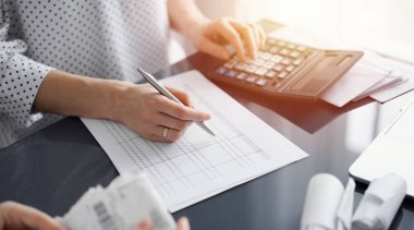 Müşteri için vergi sayarken hesap makinesi ve dizüstü bilgisayar kullanan kadın muhasebeci. İş denetimi ve finans kavramları.