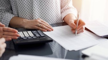 Müşteri ile vergileri sayıp tartışırken hesap makinesi ve dizüstü bilgisayar kullanan kadın muhasebeci. İş denetimi ve finans kavramları.