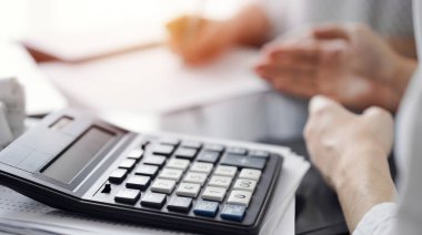 Müşteri ile vergi sayarken ve tartışırken kalem ve dizüstü bilgisayar kullanan kadın muhasebeci, hesap makinesine odaklan. İş denetimi ve finans kavramları.