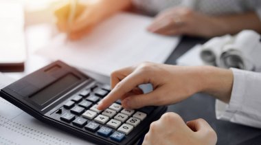 Müşteri için vergi sayarken hesap makinesi ve dizüstü bilgisayar kullanan kadın muhasebeci. İş denetimi ve finans kavramları.