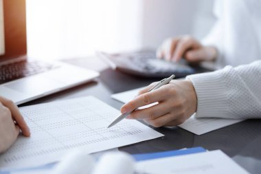 Müşteri için vergi sayarken hesap makinesi ve dizüstü bilgisayar kullanan kadın muhasebeci. İş denetimi kavramları.