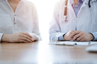 Doktor ve hasta, klinikteki ahşap masada yan yana otururken bir şey tartışıyorlar. Tıp konsepti.