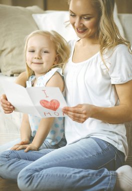 Anneler Günün kutlu olsun. Çocuk kızı annesini tebrik ediyor ve ona kalp çizimiyle kartpostal atıyor. Aile ve çocukluk kavramları.