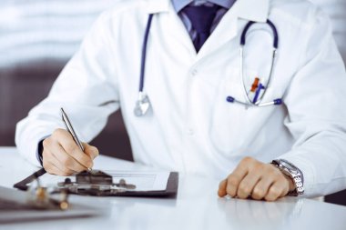 Bilinmeyen erkek doktor, klinikteki ilaç geçmişi kayıtlarıyla birlikte yakın planda oturuyor. İşteki genç doktor. Mükemmel sağlık hizmeti, tıp konsepti.