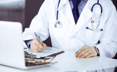 Bilinmeyen erkek doktor, klinikteki ilaç geçmişi kayıtlarıyla birlikte yakın planda oturuyor. İşteki genç doktor. Mükemmel sağlık hizmeti, tıp konsepti.