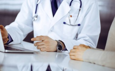 Bilinmeyen erkek doktor ve hasta kadın klinikte oturup dizüstü bilgisayar kullanırken bir şeyler tartışıyorlar. Hastanedeki en iyi sağlık hizmeti, ilaç, salgın durdurma..