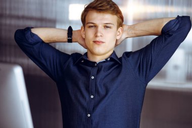 Genç sarışın işadamı ve programcı karanlık bir ofiste bilgisayarla sıkı çalıştıktan sonra el ele tutuşuyor, arka planda ışık parlıyor..