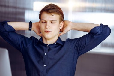 Genç sarışın işadamı ve programcı karanlık bir ofiste bilgisayarla sıkı çalıştıktan sonra el ele tutuşuyor, arka planda ışık parlıyor..