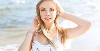 Mutlu sarışın kadın okyanus sahilinde mutlu mesut durup poz veriyor..