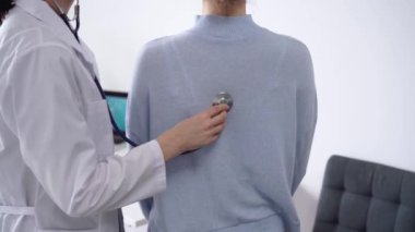 Doktor ve hasta klinikte. Beyaz önlüklü bir doktor steteskopla kadınları muayene ediyor. İlaç, terapi konsepti.