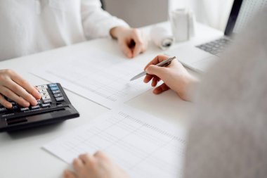 Two accountants using a laptop computer and calculator for counting taxes at white desk in office. Teamwork in business audit and finance. clipart