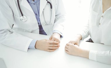 Doktor ve hasta klinikteki masada yan yana oturuyorlar. Diz üstü bilgisayarı kullanan kadın doktorların ellerine odaklan, kapat. Tıp konsepti.