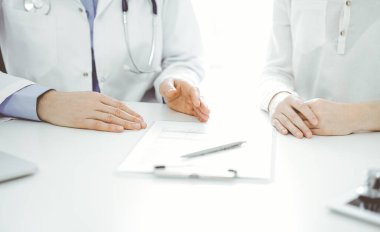 Doktor ve hasta klinikteki masada yan yana otururken sağlık sorunlarını tartışıyorlar. Sadece ellerinizi yakın tutun. Tıp konsepti.