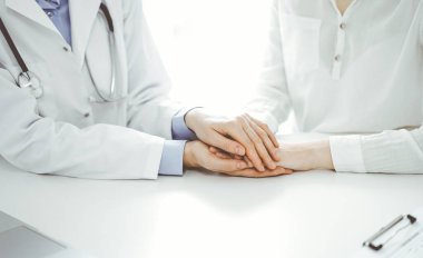 Doktor ve hasta klinikteki masada yan yana oturuyorlar. Kadın doktorlara odaklan. Kadına güven veren eller, sadece eller, yakın çekim. Tıp konsepti.