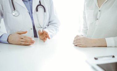 Doktor ve hasta klinikteki masada yan yana otururken sağlık sorunlarını tartışıyorlar. Sadece ellerinizi yakın tutun. Tıp konsepti.