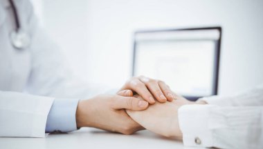 Doktor ve hasta klinikteki masada karşılıklı oturuyorlar. Kadın doktorlara odaklan. Kadına güven veren eller, sadece eller, yakın çekim. Tıp konsepti.