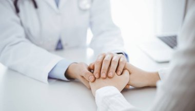 Doktor ve hasta klinikteki masada karşılıklı oturuyorlar. Kadın doktorlara odaklan. Kadına güven veren eller, sadece eller, yakın çekim. Tıp konsepti.