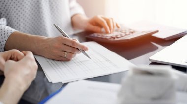 Müşteri için vergi sayarken hesap makinesi ve dizüstü bilgisayar kullanan kadın muhasebeci. İş denetimi ve finans kavramları.