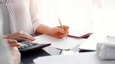 Müşteri ile vergileri sayıp tartışırken hesap makinesi ve dizüstü bilgisayar kullanan kadın muhasebeci. İş denetimi ve finans kavramları.