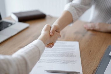 İş adamları kontrat kağıtlarının üzerinde el sıkışıyor. Tahta masaya yeni imzalanmış. Kapatın. Toplantıdaki avukatlar. Takım çalışması, ortaklık, başarı kavramı.