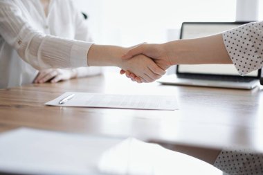 İş adamları kontrat kağıtlarının üzerinde el sıkışıyor. Tahta masaya yeni imzalanmış. Kapatın. Toplantıdaki avukatlar. Takım çalışması, ortaklık, başarı kavramı.