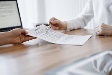 İş kadını avukat, ofisteki ahşap masada meslektaşı ya da müvekkili için bir şey itiraf eden özel sözleşmeye işaret ediyor. İş adamları takım çalışması ve ortaklık, toplantı konsepti.