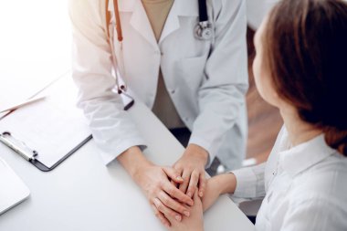 Doktor ve hasta klinikteki masada oturuyorlar. Dikkatimizi kadın doktorlara, güven veren kadınlara verelim. Kapatalım. Mükemmel tıbbi servis, empati ve tıp konsepti..