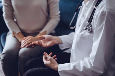 Doktor ve hasta klinikteki kanepede oturmuş bir şey tartışıyorlar. Steteskopa odaklan, kapat. Mükemmel tıbbi hizmet ve tıp konsepti.