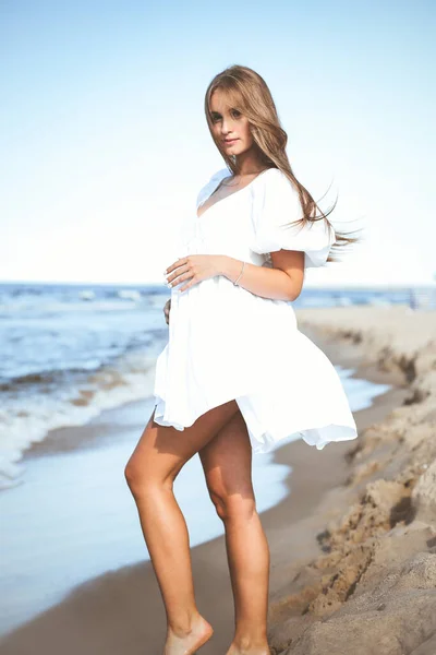 穿着白色夏装站在海滩上的快乐而美丽的女人 — 图库照片